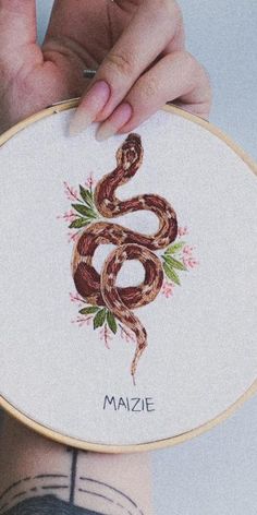 a person holding up a cross - stitch pattern with a snake on it