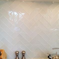 a kitchen with white tile backsplash and stainless steel faucets on the counter