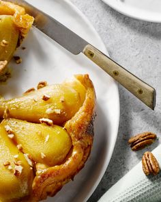 a white plate topped with sliced pineapples next to a knife and fork on top of a table