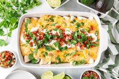 an enchilada dish in a white casserole with cilantro and lime