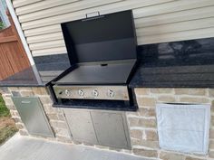 an outdoor bbq with two grills on the side of it and a towel hanging from the door