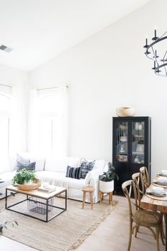 a living room filled with furniture and a dining table in front of a large window