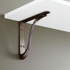 a close up of a metal hook on a wall with a white shelf above it