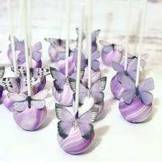 there are many butterflies on the cake popss that have been decorated with purple and white icing