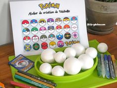 a green tray topped with lots of white eggs next to markers and pencils on top of a wooden table