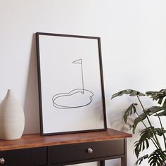 a black and white photo sitting on top of a wooden table next to a potted plant