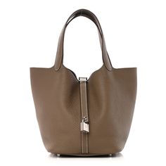 This is an authentic HERMES Taurillon Clemence Picotin Lock 22 MM in Etoupe. This stunning tote is crafted of luxuriously soft Clemence calfskin leather in taupe, in a relaxed bucket style, with silver hardware. The bag features a unique one-piece reinforced design with leather top handles and a thin cross-over strap. The top is open to a matching suede interior. Hermes Picotin, Leather Top, Silver Hardware, Calf Skin, Handles, Purse, One Piece, Leather, Silver