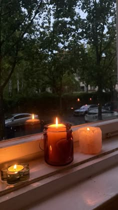 two candles are sitting on a window sill in front of the windowsill with cars outside