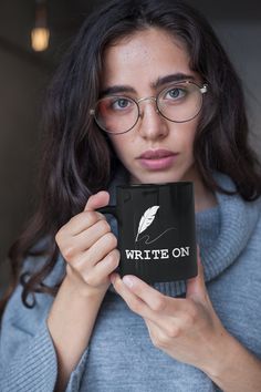 a woman wearing glasses holding up a coffee mug