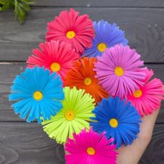 colorful paper flowers are in the palm of someone's hand