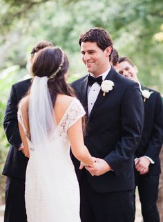 a bride and groom standing next to each other in front of some men wearing tuxedos