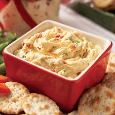 a red bowl filled with dip surrounded by crackers