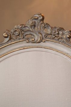 an ornately decorated bed frame with gold trimmings and white linen upholstered