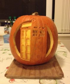 a carved pumpkin sitting on top of a cutting board with a phone booth in it