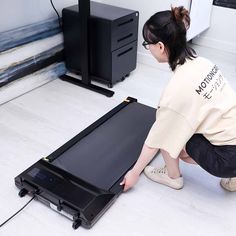 a woman kneeling down next to an electronic device