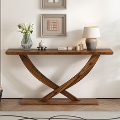 a wooden table sitting in the middle of a room next to a vase with flowers on it