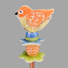 an orange bird sitting on top of a wooden stick in front of a gray background