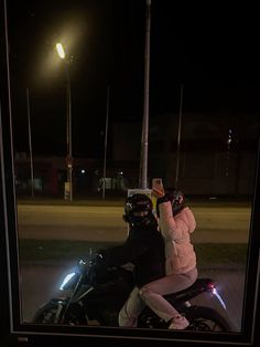 a person on a motorcycle at night taking a selfie with their cell phone in the dark