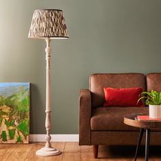 a living room with a couch, lamp and painting on the wall in it's corner