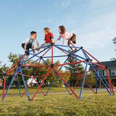 three children are playing on a wooden structure in the grass with their arms around each other