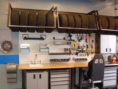 a garage with lots of tires hanging from the ceiling and cabinets on the wall behind it