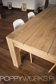 a wooden table with four white chairs around it on a hard wood flooring area