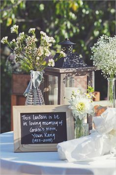 two vases filled with flowers sitting on top of a table next to a sign