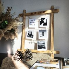 a wooden frame with pictures and pine cones on it next to a vase filled with flowers