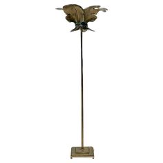 a metal floor lamp with a flower on it's base and two birds flying over the top