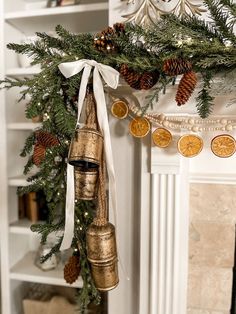 a christmas tree with bells hanging from it's branches and pine cones on the mantle