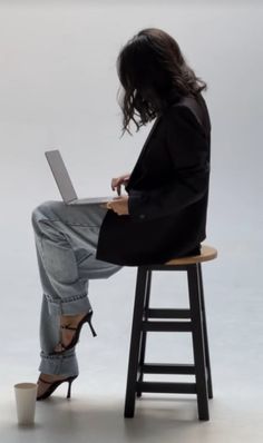 a woman sitting on a stool using a laptop computer