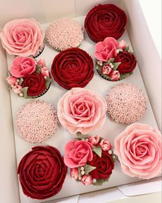 cupcakes decorated with pink and red flowers in a box