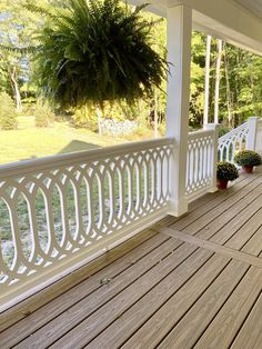 a wooden porch with white railings and potted plants