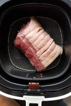 raw meat being cooked in an air fryer with the lid open to show it's skin