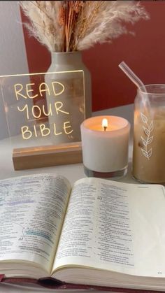 an open bible next to a lit candle on a table with a sign reading read your bible