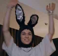 a man wearing a bunny ears hat and holding his hands up in the air