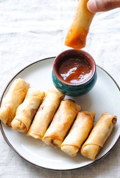 a person dipping sauce onto some food on a plate