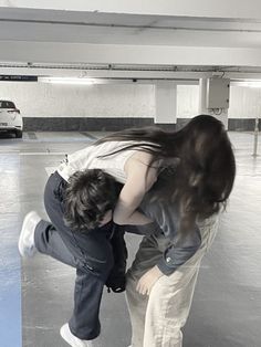 two people in an empty parking garage with one person holding the other's head