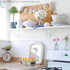 a white stove top oven sitting inside of a kitchen next to a counter topped with plates and bowls