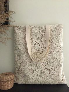 a white lace bag sitting on top of a wooden table next to a basket and plant