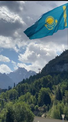 a flag flying in the wind with mountains in the background