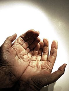 an older person holding their hands up in front of a light that is shining on the wall