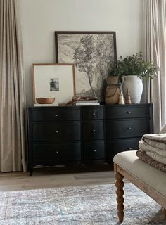 a bedroom with a bed, dresser and pictures on the window sill in front of it