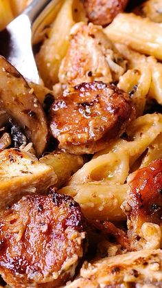 a plate with pasta, meat and sauce on it next to a fork in the bowl