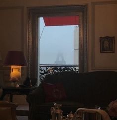 a living room filled with furniture next to a window covered in fog and lightening