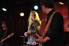 two people are playing music on stage with one woman singing and the other man holding a guitar