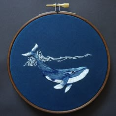 a blue embroidered whale with waves on it's back is shown in the hoop