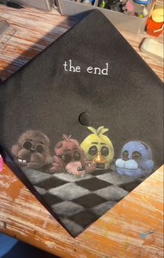 a graduation cap with the words, the end on it and five cartoon characters painted on it