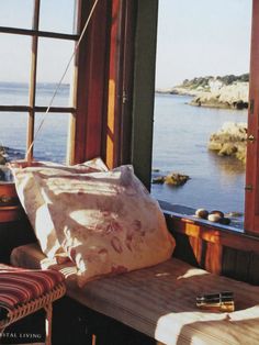 a window with a view of the water and land outside it is sitting on a bench