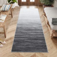 a long gray rug is on the floor in a room with wooden floors and windows